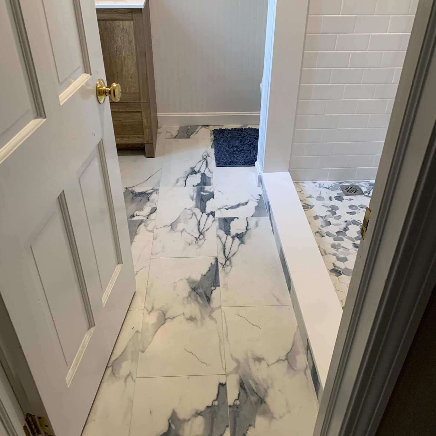 Bathroom with marble-look tile flooring, shower, and a vanity. A door is partially open.