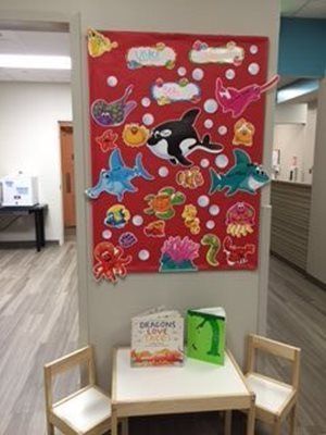Awaiting area with a red underwater-themed display, small table, and chairs. Books and colorful sea creature decorations.