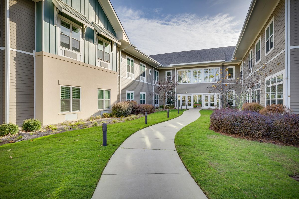 A concrete walkway leading to a large building with a lot of windows.