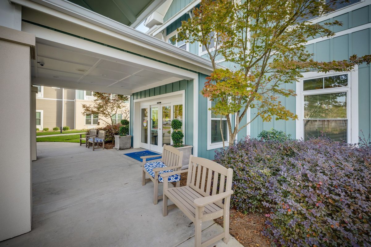 A patio with a bench and chairs in front of a building.
