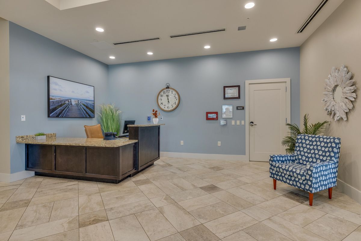 A lobby with a clock on the wall and a chair