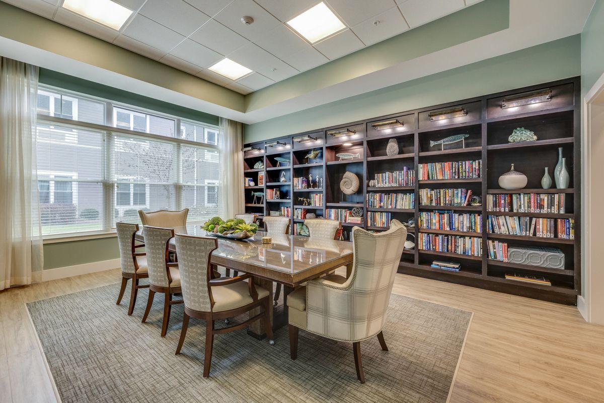 A dining room with a table and chairs in front of a bookshelf.