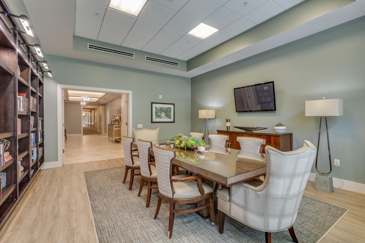 A dining room with a table and chairs and a television.