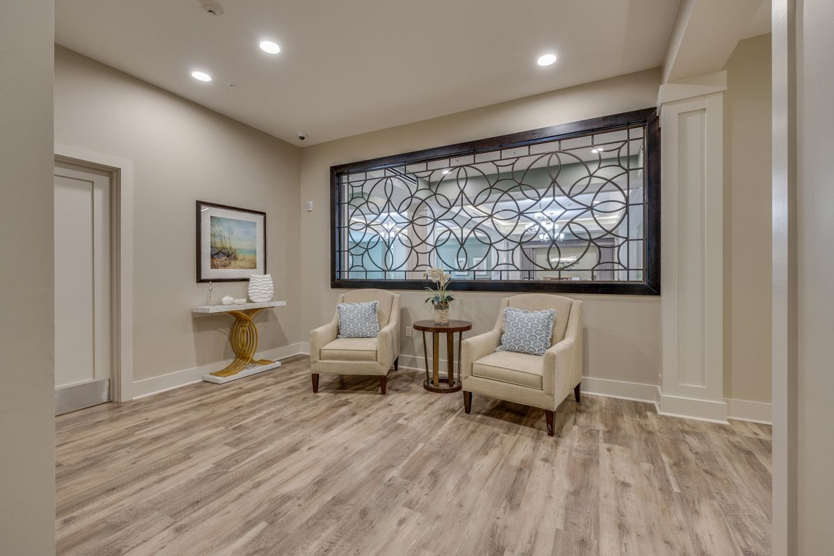 A living room with two chairs , a table and a stained glass window.