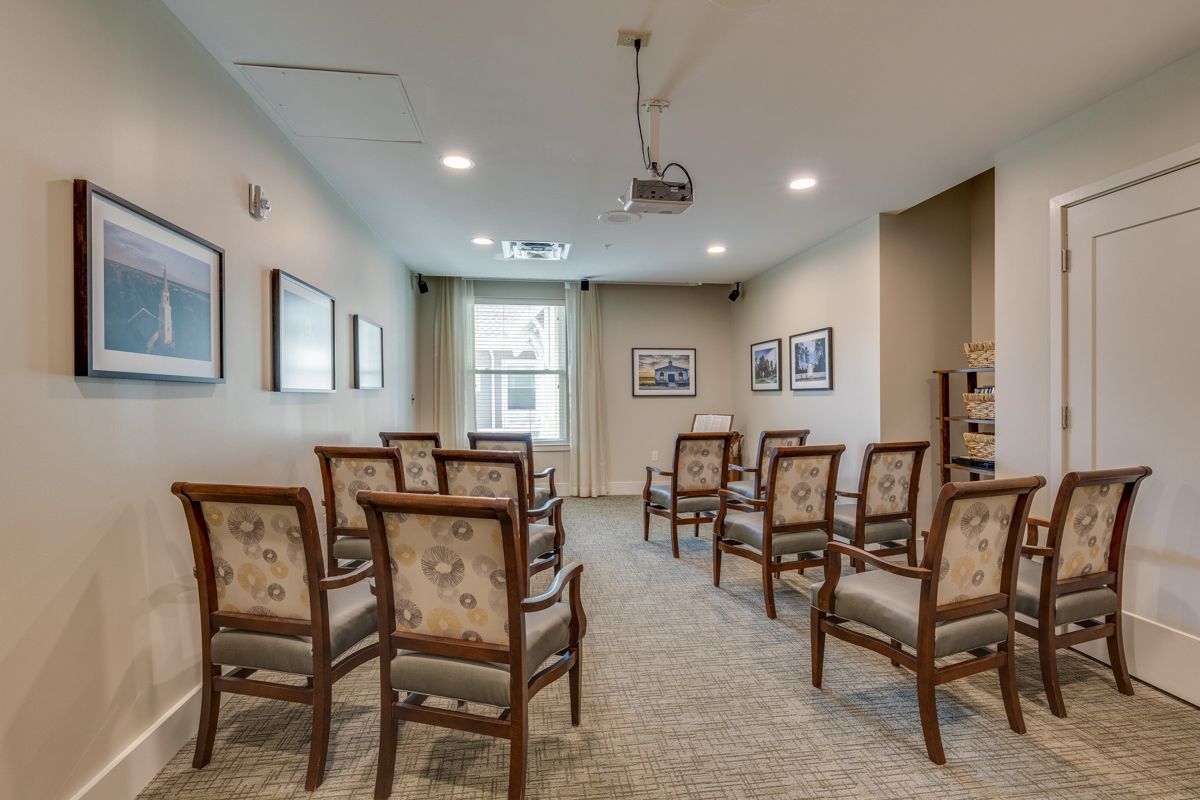 A room with rows of chairs and a projector on the ceiling.