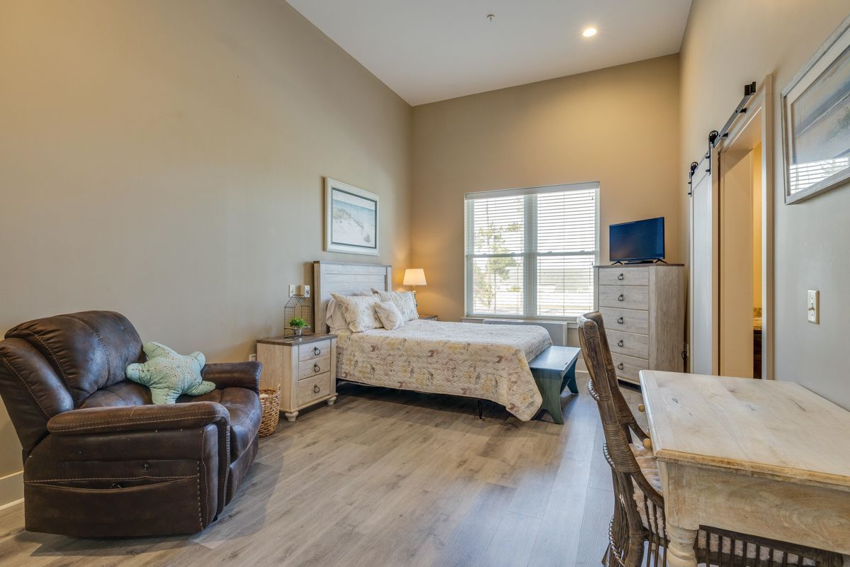 A bedroom with a bed , chair , desk and television.