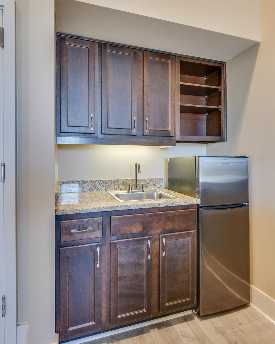 A kitchen with wooden cabinets and a stainless steel refrigerator