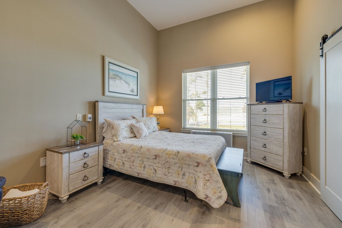 A bedroom with a king size bed , dresser , nightstand , and television.