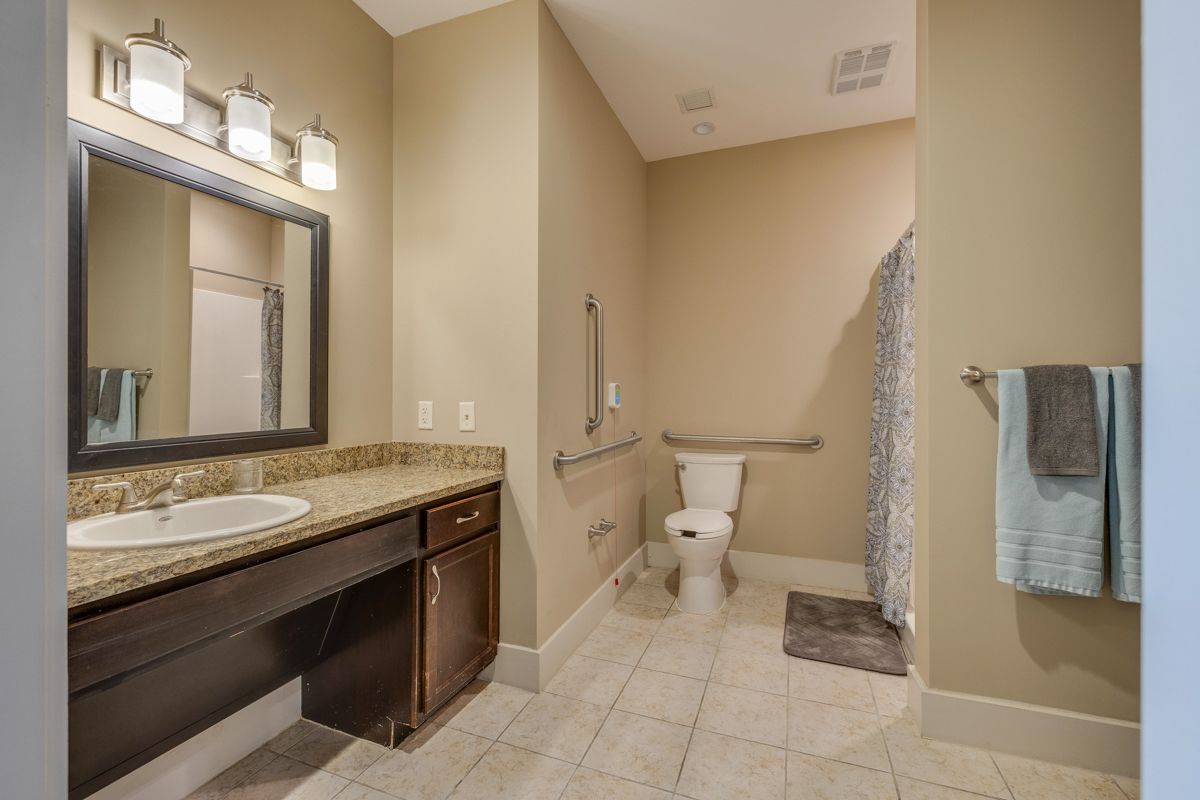 A bathroom with a sink , toilet , shower and mirror.
