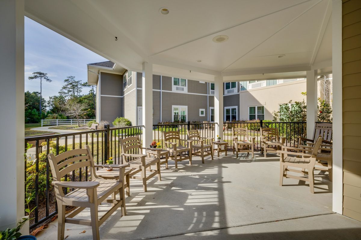 There are a lot of chairs and tables on the porch.