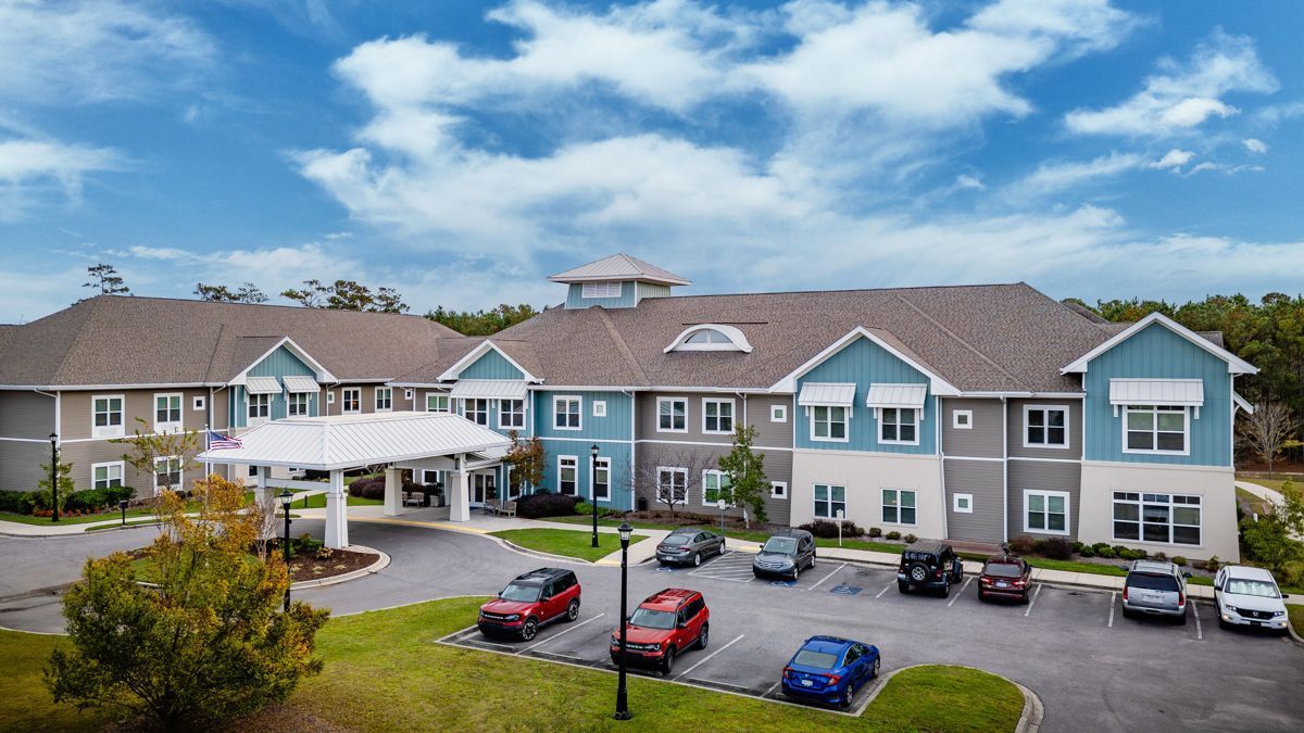 An aerial view of a large apartment building with cars parked in front of it.