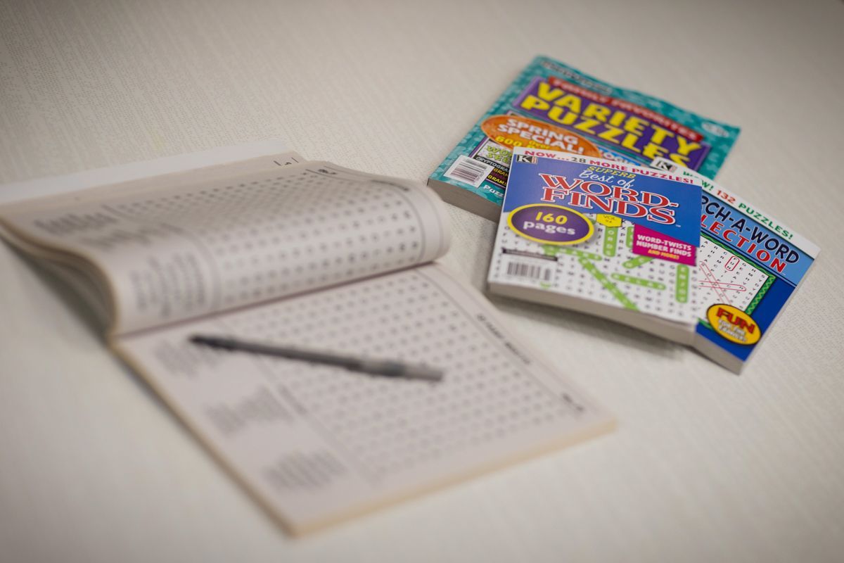 A notebook with a pen and two puzzle books on a table.