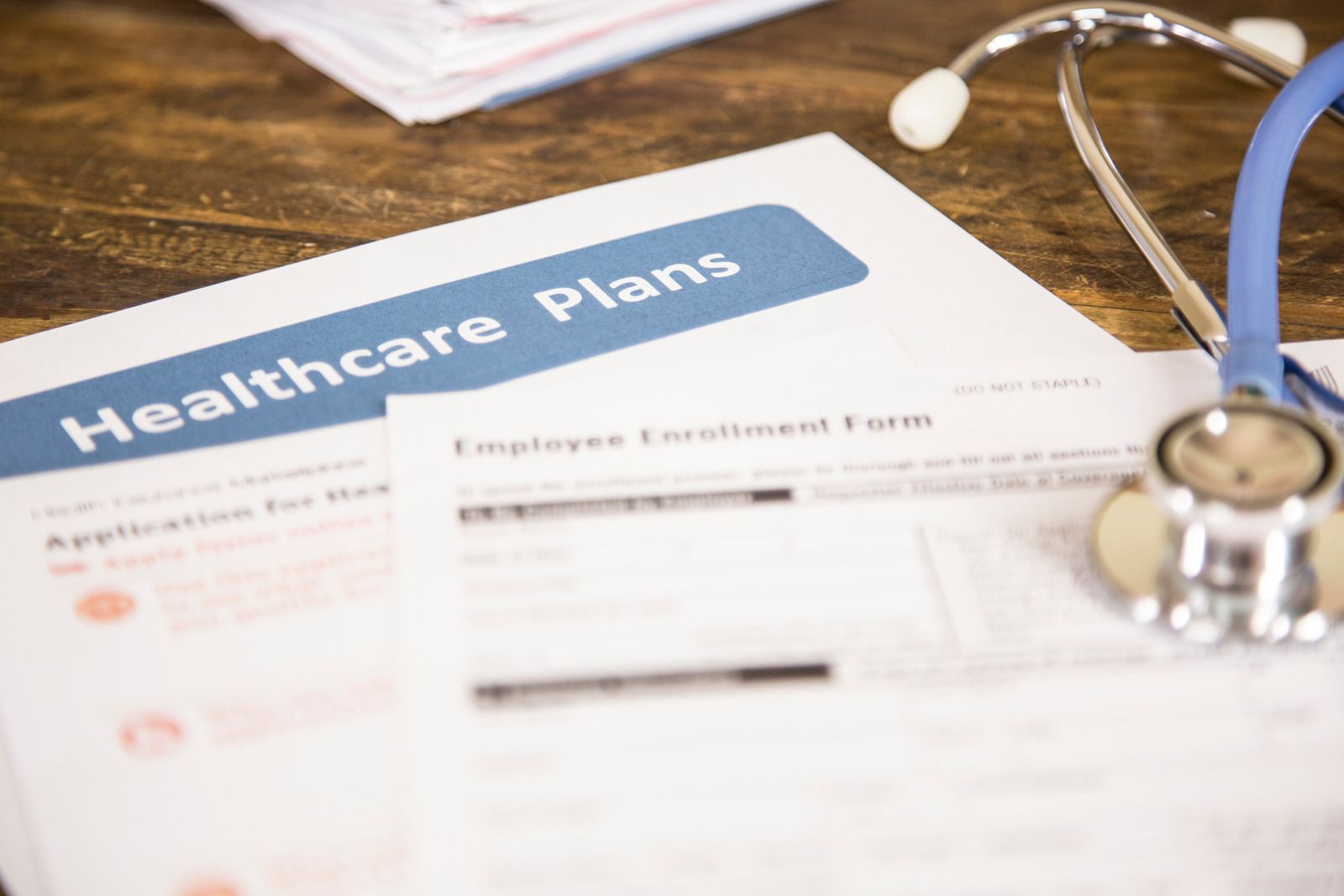Healthcare plan documents and stethoscope on a wooden table.