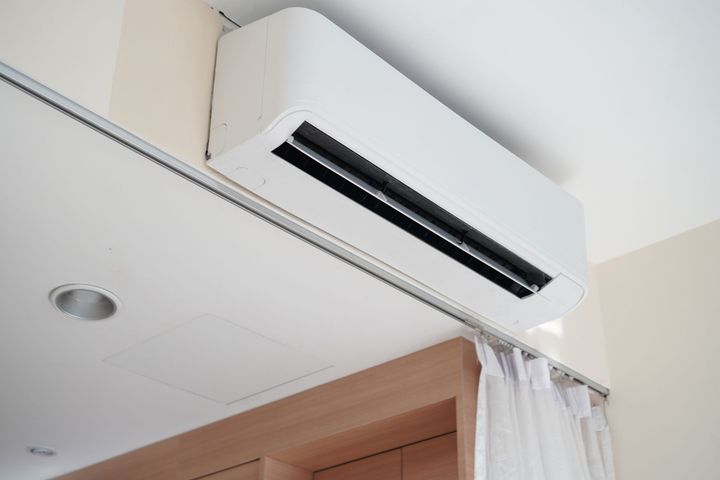 A white air conditioner is hanging from the ceiling in a room.