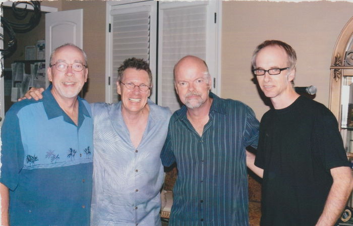 A group of four men posing for a picture together