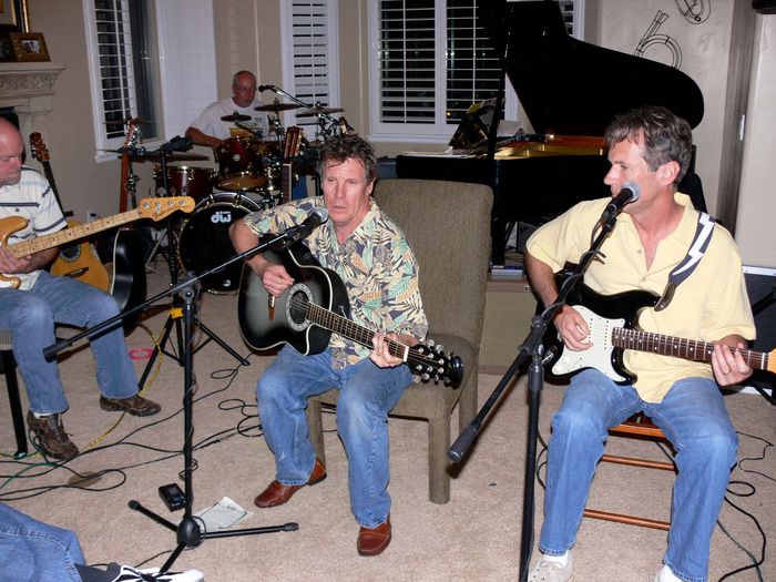 A group of men are playing guitars and singing into microphones