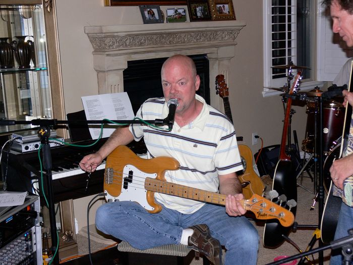 A man singing into a microphone while playing a guitar