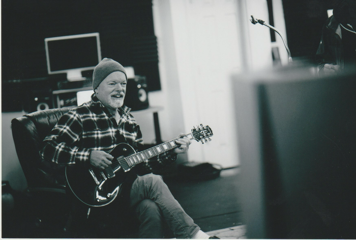 A man is sitting in a chair playing a guitar