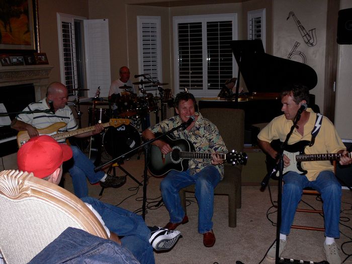 A group of men are playing guitars in a living room