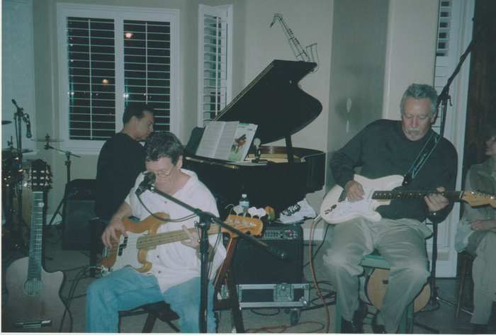 A group of men are playing guitars in front of a piano