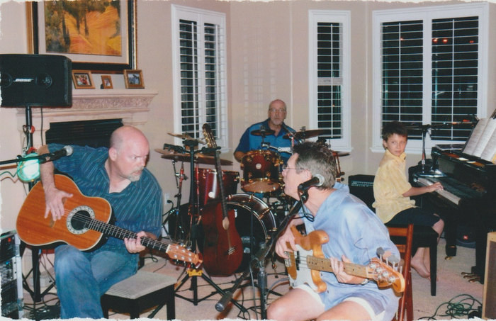 A group of men are playing guitars and drums in a living room