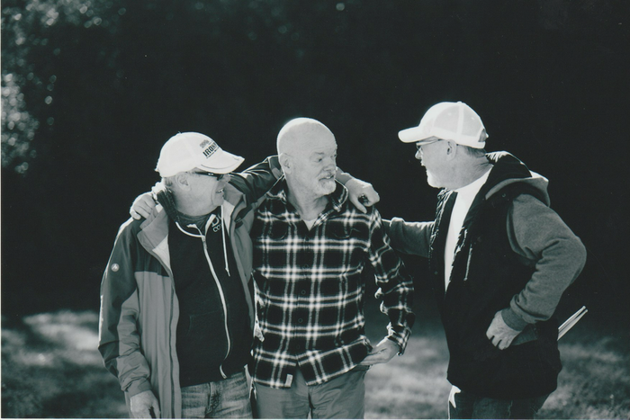 Three men are standing next to each other in a black and white photo