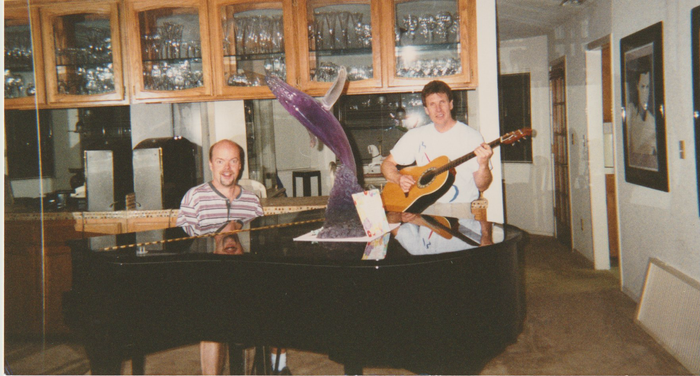 A man playing a guitar next to another man playing a piano