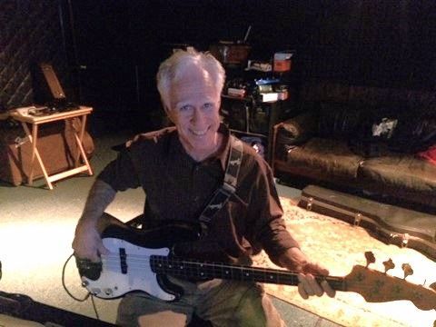 A man is holding a guitar in a dark room.