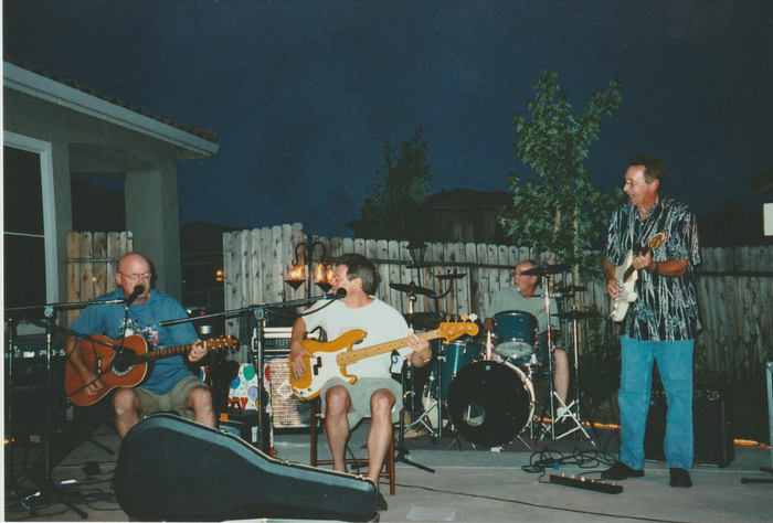 A group of men are playing guitars and singing into microphones