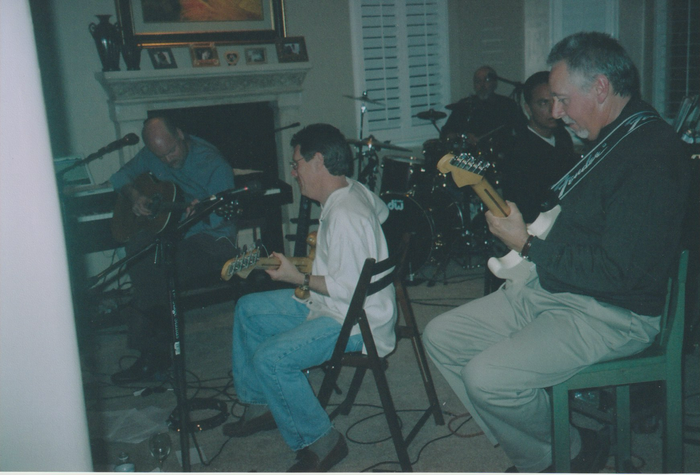 A group of men are playing guitars in a living room.