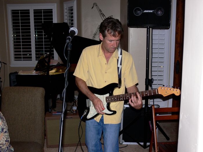 A man in a yellow shirt is playing a guitar