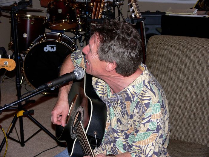 A man singing into a microphone in front of a dw drum