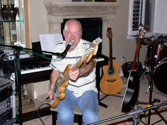 A man singing into a microphone while playing a guitar