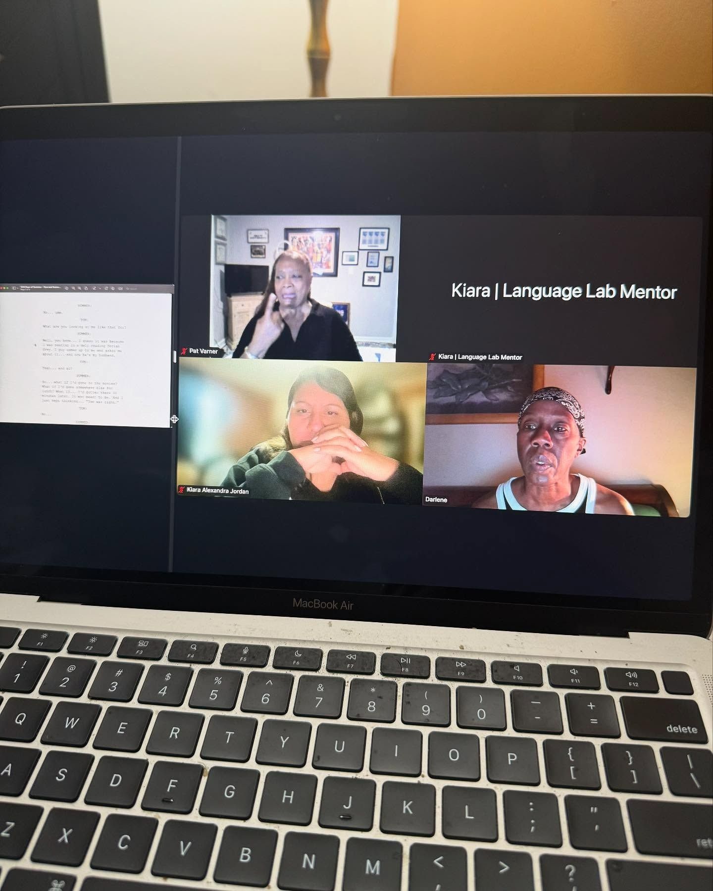 Laptop screen shows a Zoom call with three participants and a whiteboard. Keyboard in focus.