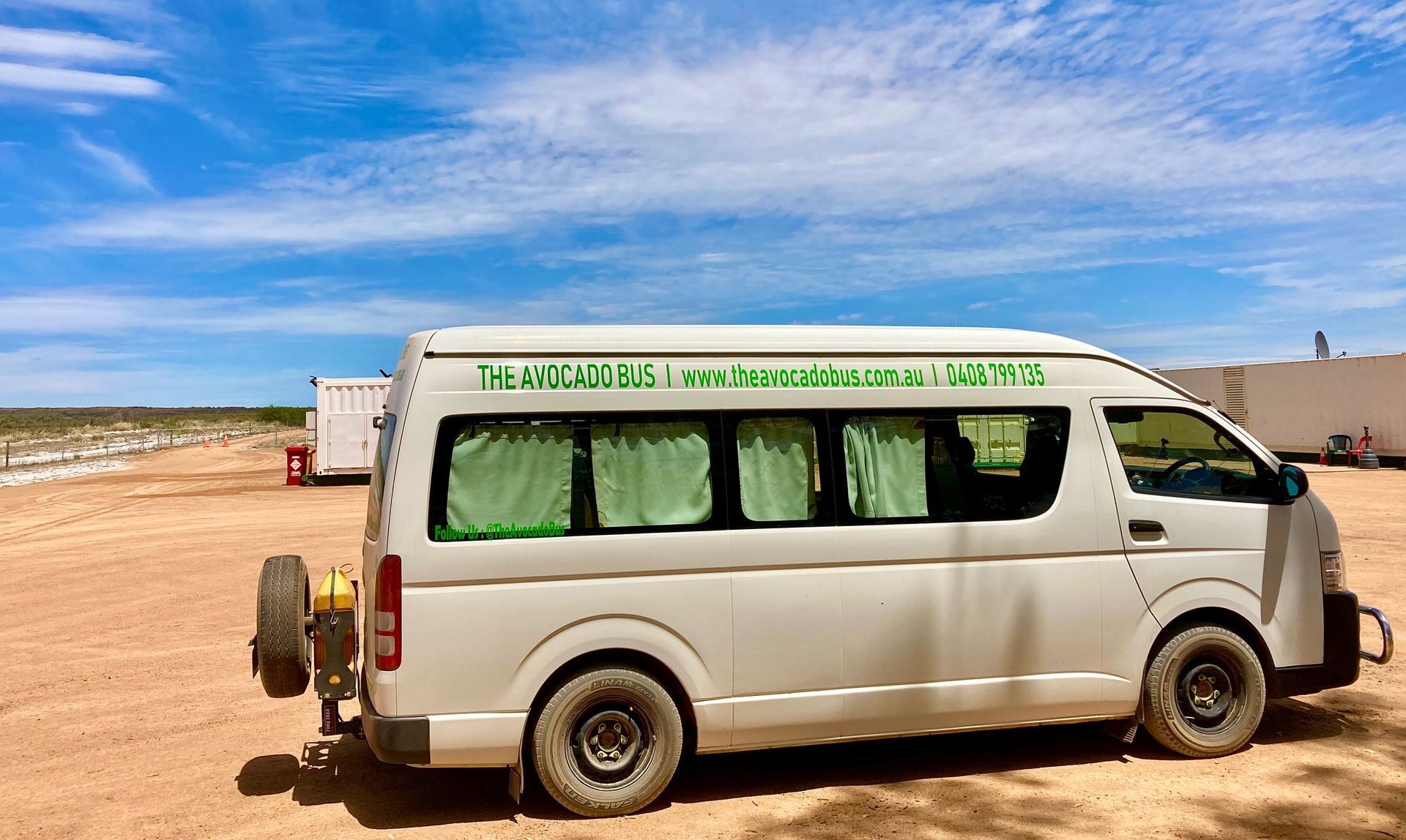 A white van is parked in a dirt field.