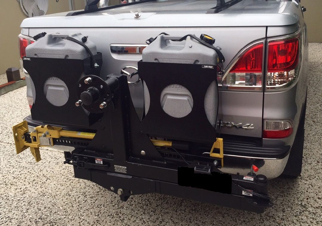 A silver 4wd with two jerry cans attached to the back of it