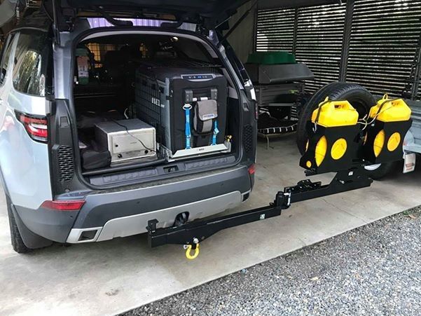 A 4wd with a tyre rack attached to it is parked in a garage.