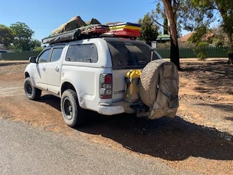 A white 4WD with a tent on top of it is parked on the side of the road.