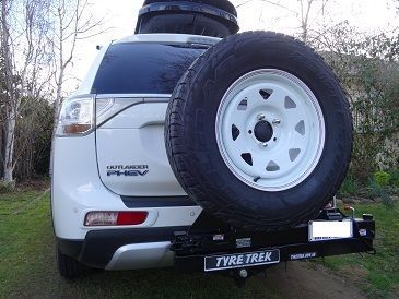 A white 4wd with a spare tyre attached to the back of it.
