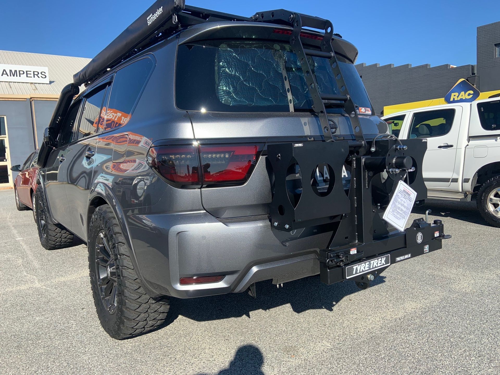 A gray suv with a bike rack on the back is parked in a carpark.