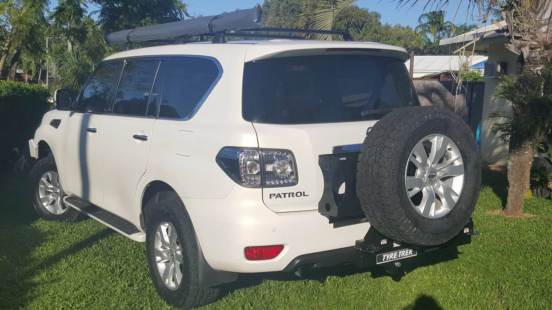 A white suv with a spare tyre attached to the back is parked in the grass.