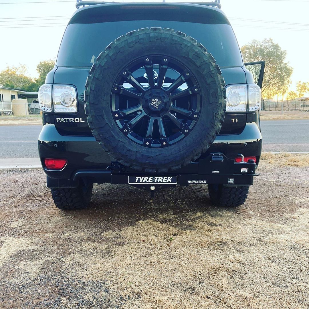 A black patrol suv is parked on the side of the road