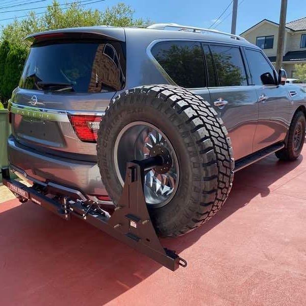 A silver suv with a spare tyre attached to the back of it