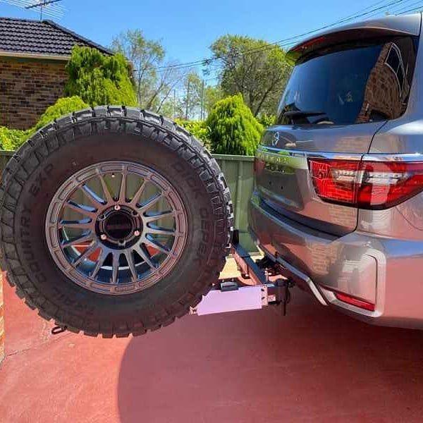 A silver suv with a spare tyre attached to the back of it.