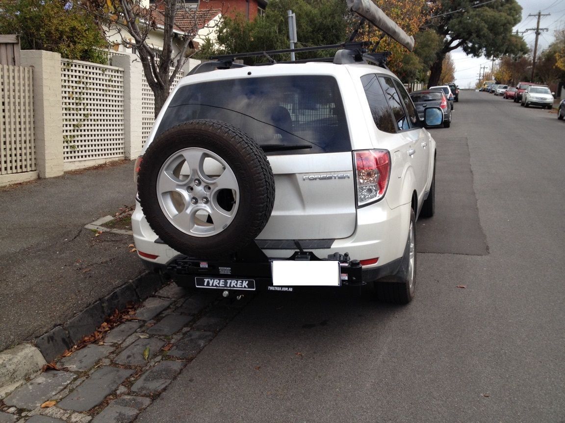 A white subaru is parked on the side of the road
