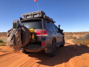 A suv is parked on a dirt road in the outback.