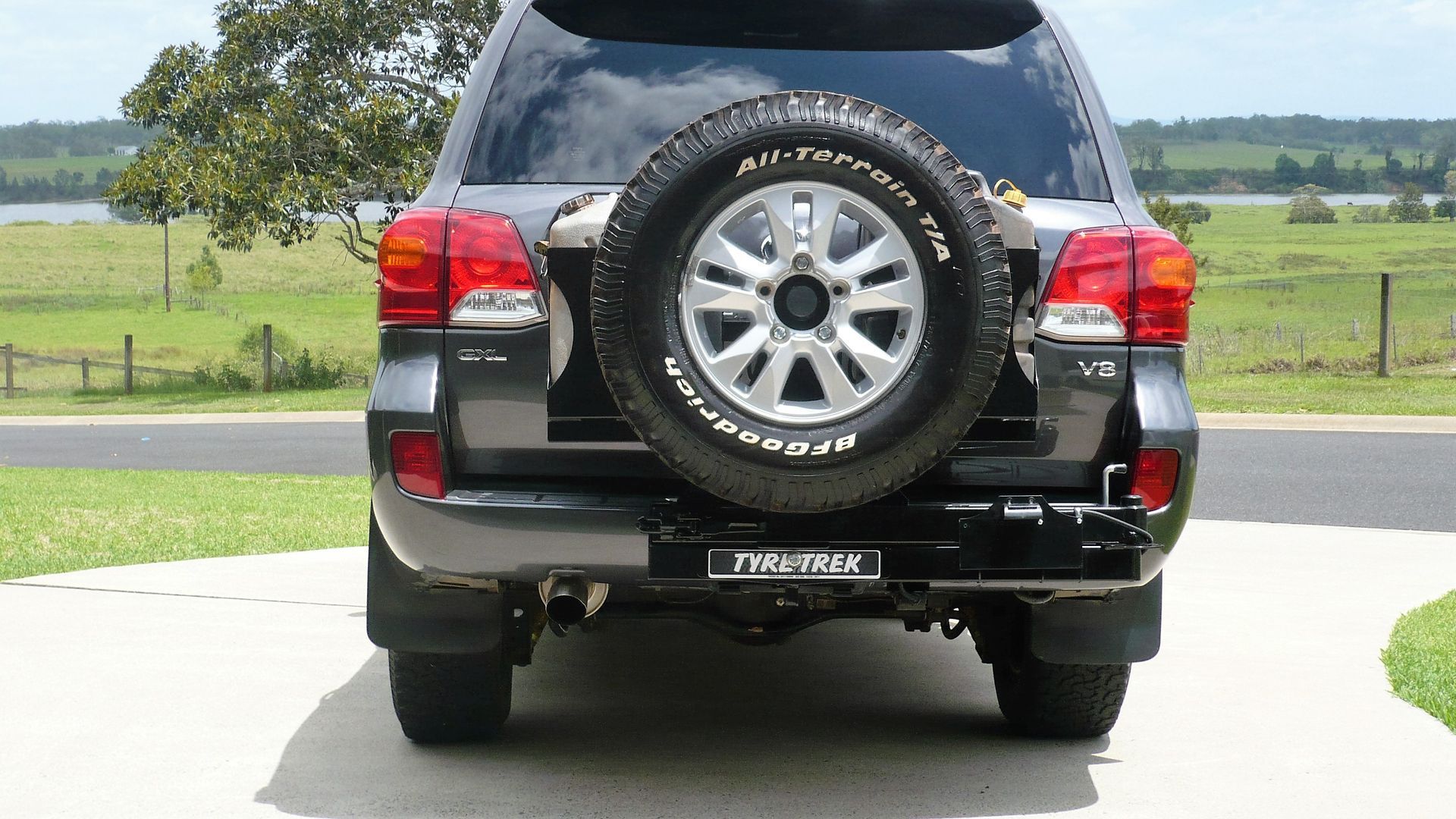 A black suv with a spare tyre on the back is parked in a driveway