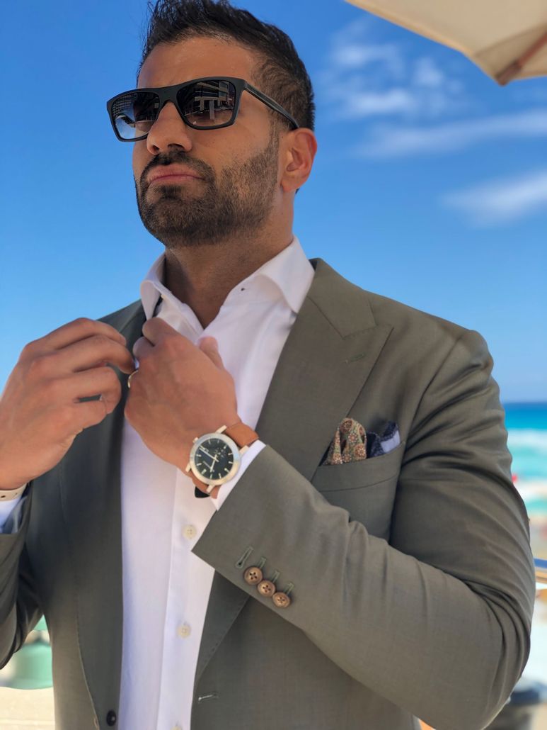 Kamran Ali wearing a bespoke olive-green suit and sunglasses