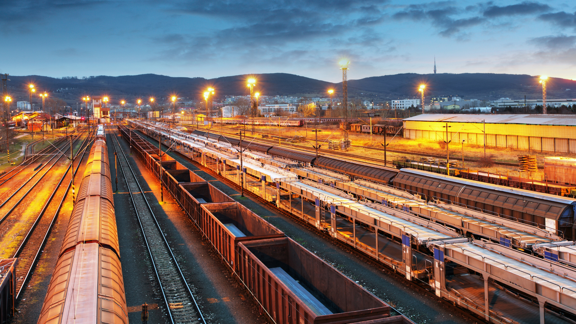 A train yard filled with lots of train cars at night.