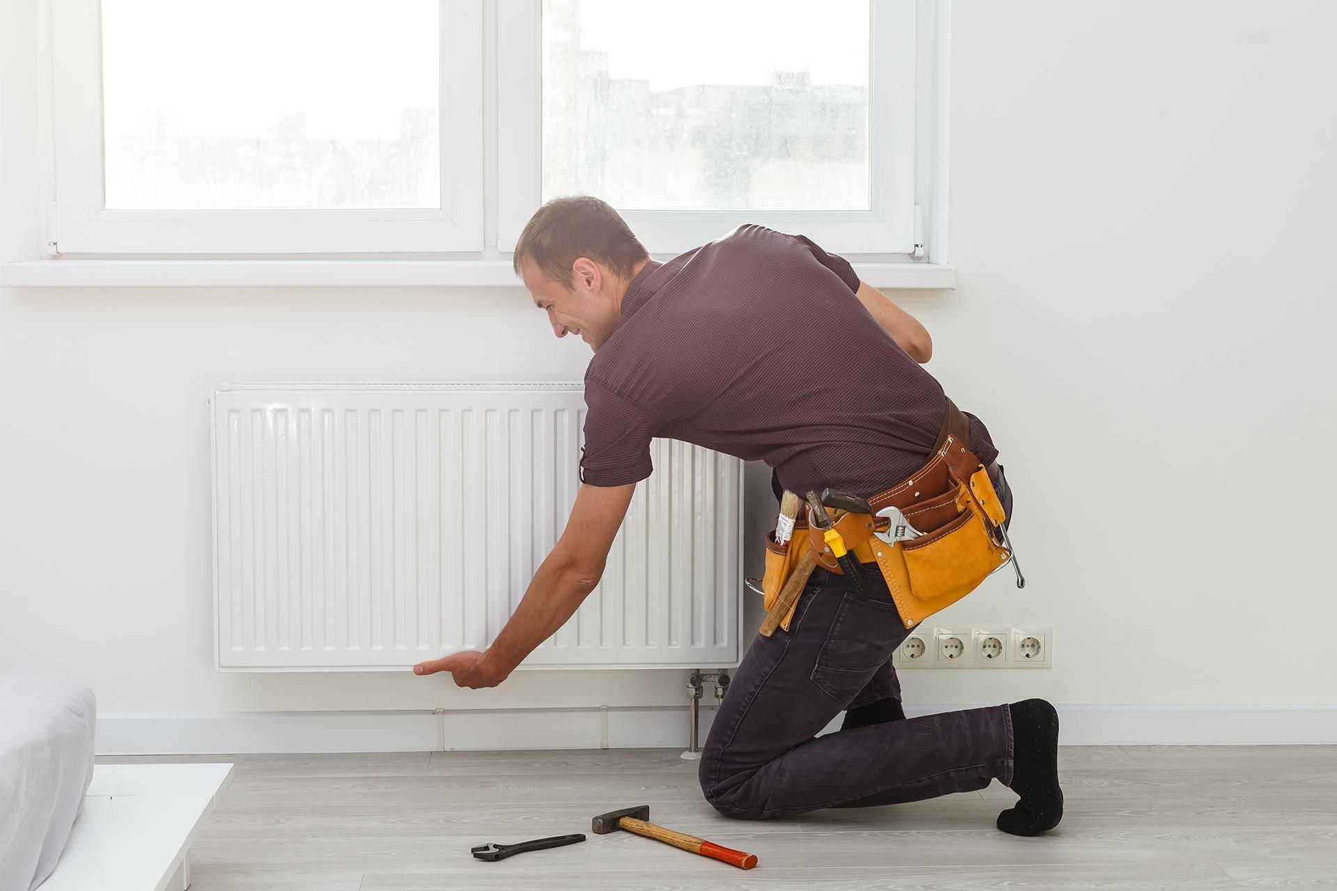 An HVAC technician is repairing the radiator in the room.